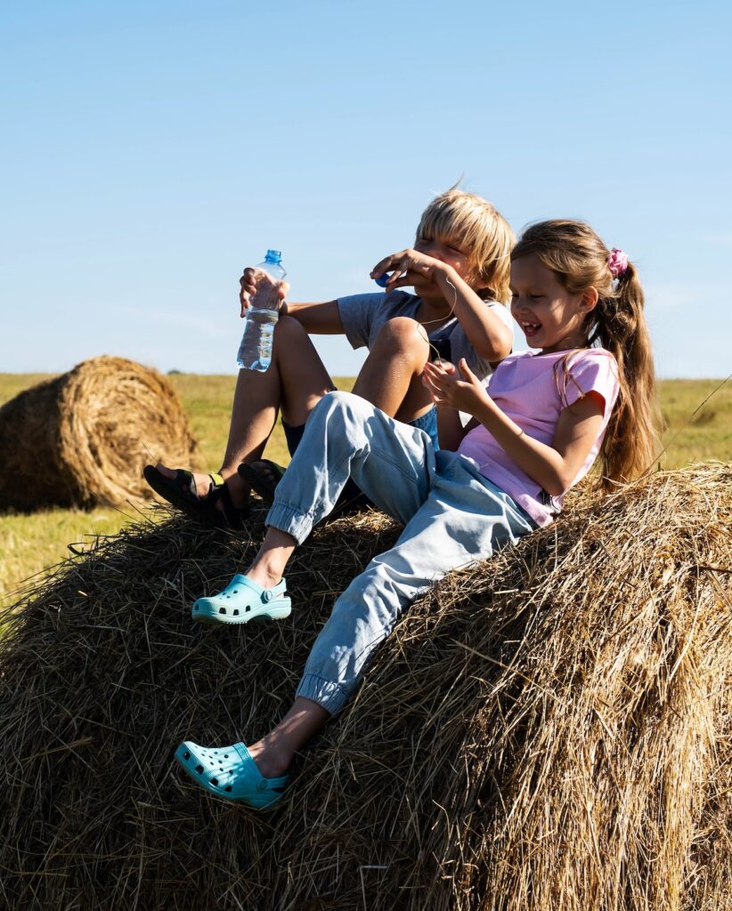 Girl and Boy Having Fun in Haystack. Summertime in the Country.